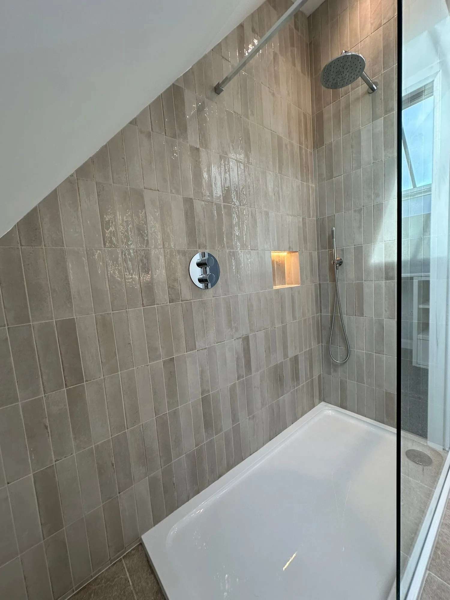 Contemporary loft ensuite walk-in shower with narrow stone tiles and lit recess