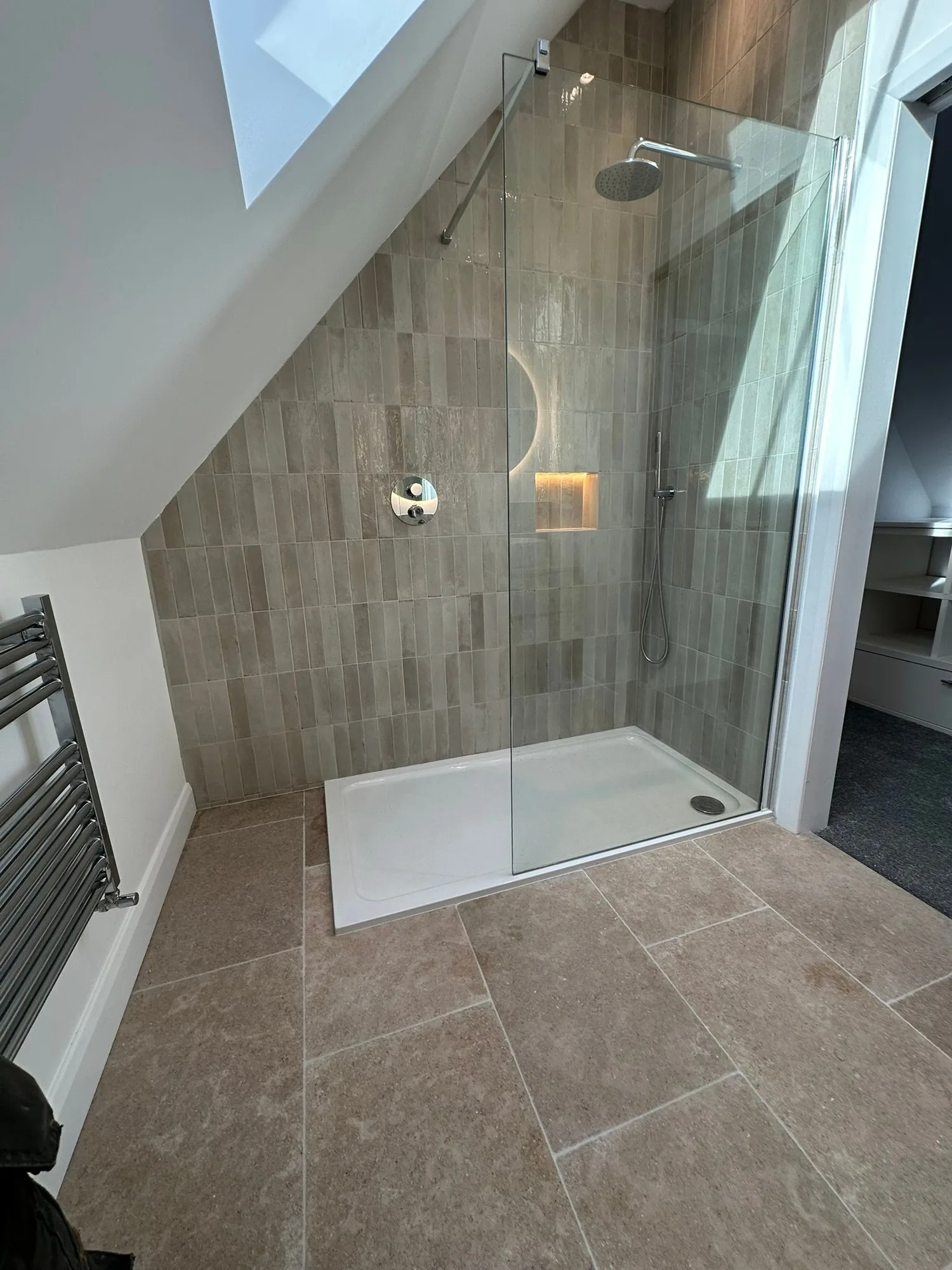 Wider view of the contemporary loft ensuite shower with stone floor